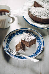 Slice of chocolate fridge tart with coconut shreds and mug of coffee - IPF00545