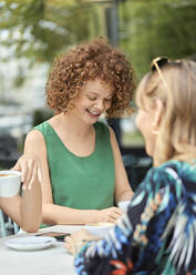 Redheaded young woman meeting with friends in a cafe - ZEDF03620