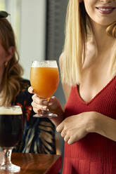 Woman holding glass of craft beer in a pub - ZEDF03631