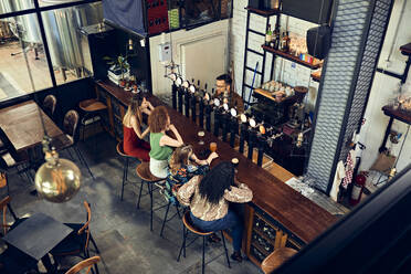 Female friends socializing at the counter in a pub - ZEDF03649