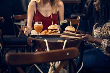Weibliche Freunde essen einen Burger in einer Kneipe - ZEDF03656