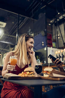 Glückliche Frau mit Freund in einer Kneipe bei einem Bier und einem Burger - ZEDF03661
