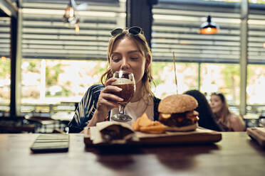 Woman having a beer and a burger in a pub - ZEDF03663