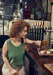 Woman having tapas at the counter in a pub - ZEDF03667