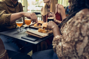 Freunde sitzen am Tisch in einer Kneipe bei Burger und Bier - ZEDF03669