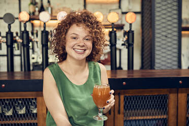 Portrait of a smiling woman in a pub having a beer - ZEDF03671