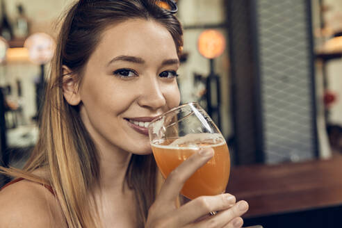 Porträt einer lächelnden Frau in einer Kneipe, die ein Bier trinkt - ZEDF03677