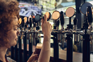 Barkeeperin zapft Bier in einer Kneipe - ZEDF03692