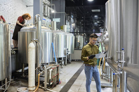 Man and woman working in craft brewery stock photo