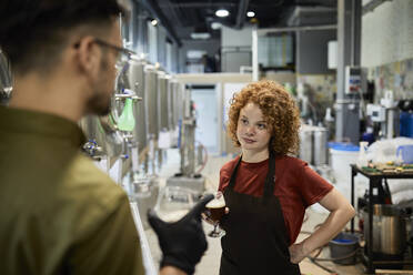 Mann und Frau arbeiten in einer handwerklichen Brauerei und prüfen die Qualität eines Bieres - ZEDF03708