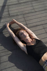 Woman stretching while lying on footbridge - MTBF00619