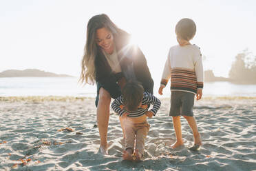 Frau spielt mit Kindern am Strand - CMSF00127
