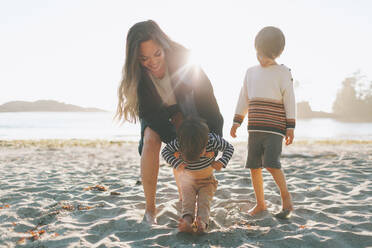 Woman playing with children at beach - CMSF00127