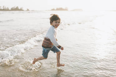 Cute girl wearing underwear playing in water on beach stock photo