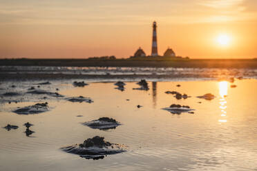 Deutschland, Schleswig-Holstein, Westerhever, Küstenpfütze bei Sonnenaufgang mit Leuchtturm Westerheversand im Hintergrund - KEBF01623