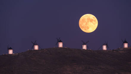 Amazing scenery of majestic full Moon over valley with windmills in sundown - ADSF12649