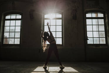 Silhouette einer Frau beim Sport in einer verlassenen Fabrik - GMLF00515