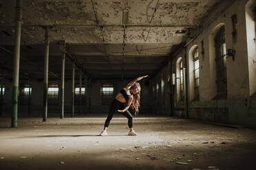 Woman stretching while exercising at abandoned factory - GMLF00518
