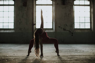 Athlete exercising yoga position at abandoned factory - GMLF00536