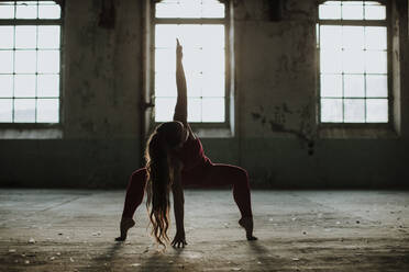 Sportler übt Yoga-Position in verlassener Fabrik - GMLF00536