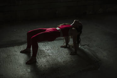 Sportler beim Üben der nach oben gerichteten Plank-Pose in einer verlassenen Fabrik - GMLF00541