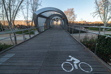 Perspektive Blick auf gepflasterten hölzernen Radweg zu futuristischen Galerie im Park in der Stadt während des Abends - ADSF12673