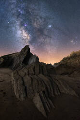 From below of rough cliff peak under milky way colorful blue night sky and shiny stars on background - ADSF12715