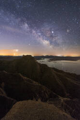 From above of tops of mountains and rocky valley with calm lake on background under colorful sky with milky way - ADSF12722