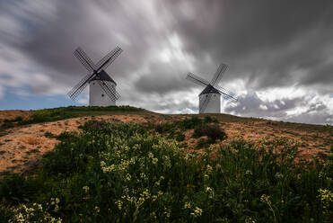 From below old traditional windmills located on top of hill on cloudy day in countryside - ADSF12729