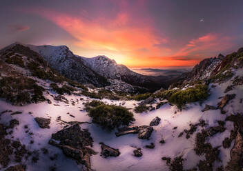 Atemberaubender Blick auf Bergkamm mit weißem Schnee bedeckt gegen lebendige Sonnenuntergang Himmel in bewölkten Abend in der Natur gelegen - ADSF12739