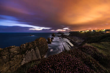 Prächtige Szenerie des felsigen Ufers des Ozeans mit rauen Felsen und ruhigem Wasser unter majestätischem Himmel bei Sonnenuntergang - ADSF12760