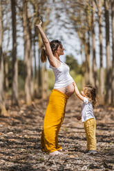 Schwangere Mutter und kleine Tochter haben Spaß im Park - ADSF12775