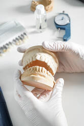 From above of crop anonymous dentist in medical gloves working with dental prosthesis in modern laboratory - ADSF12804