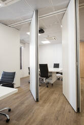 Interior of modern office with table and chairs located in room separated by white panels - ADSF12875