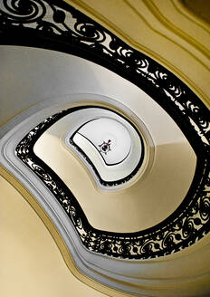 Von unten weiße elegante Wendeltreppe mit schwarzem Ziergeländer im Inneren eines klassischen Gebäudes - ADSF12904