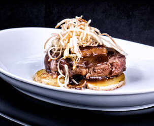 Delectable fried steak garnished with mushrooms and served with potato on dish in luxury restaurant - ADSF12959