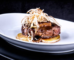 Köstliches gebratenes Steak, garniert mit Champignons und serviert mit Kartoffeln auf einem Teller im Luxusrestaurant - ADSF12959