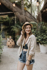 Lächelnde Frau mit Hut posiert vor einer Hütte - SMSF00180