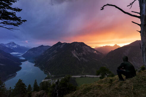 Österreich, Tirol, Silhouette eines Mannes, der den Plansee und die umliegenden Berge bei Sonnenuntergang bewundert - MALF00157