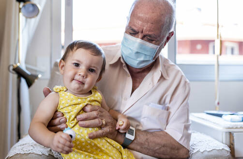 Grandfather with protective mask and baby girl at home - GEMF04093