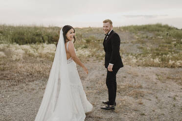 Smiling bridegroom standing in field - SMSF00254