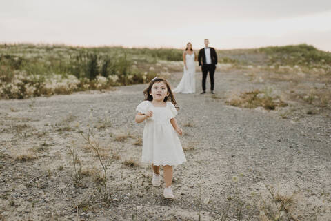 Cute daughter running while parents standing against sky stock photo