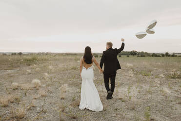 Bride and groom with heart shape balloons walking against sky - SMSF00279