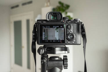 Close-up of digital camera on tripod in living room at home - EGAF00667