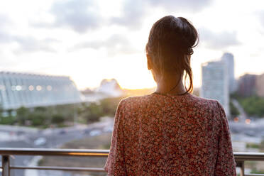 Woman standing in balcony while looking at sunset - EGAF00671