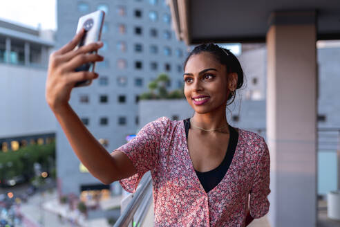 Glückliche Frau macht Selfie auf dem Balkon - EGAF00678