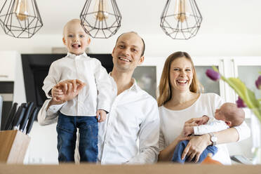 Eltern lächelnd, während sie ihre kleinen Jungen zu Hause halten - SAJF00091