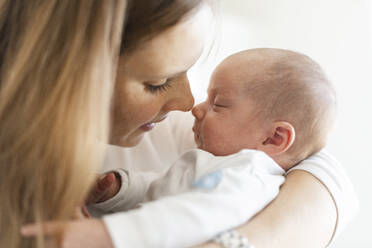 Nahaufnahme einer Mutter, die ihr schlafendes Baby zu Hause in die Arme nimmt - SAJF00100