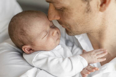 Father embracing his sleeping baby boy in arms at home - SAJF00108