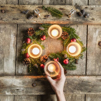 Hand of woman touching glass cover of candle burning on Advent wreath - EVGF03704